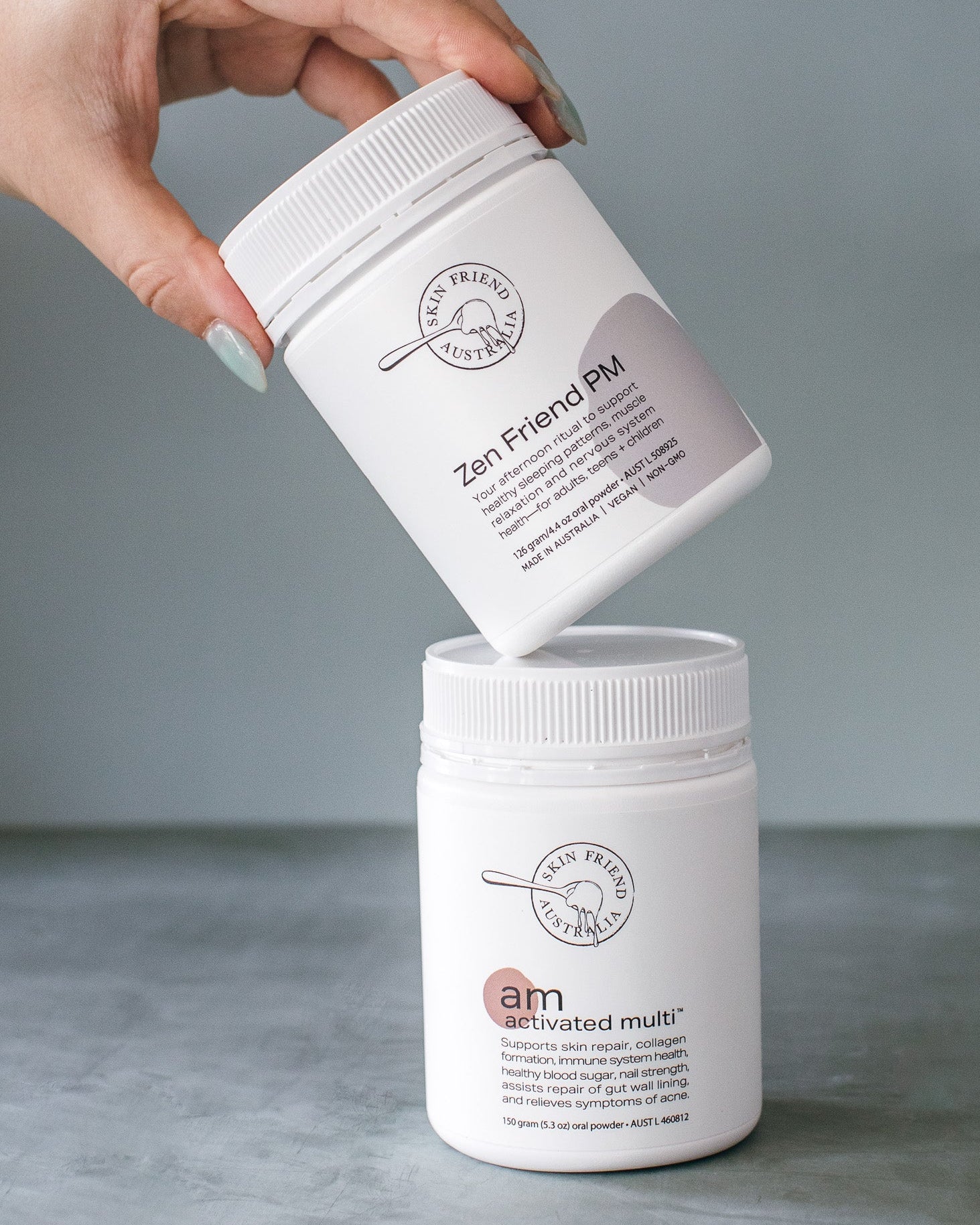 Hand holding a white container labeled 'Zen-Friend PM' with another container on a gray surface.